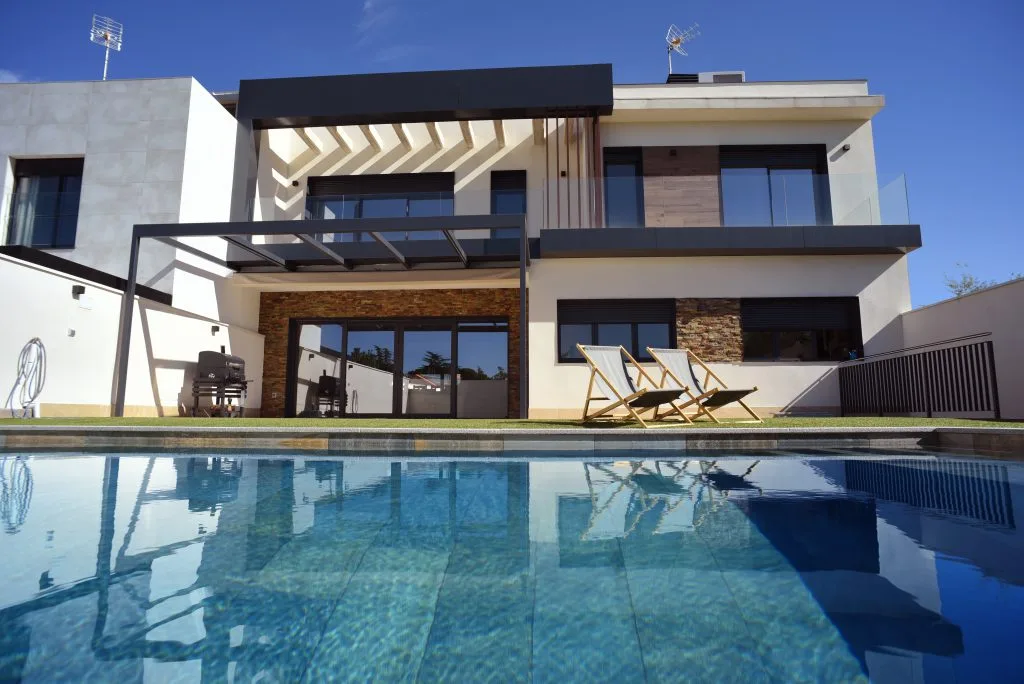 Vivienda unifamiliar con fachada de porcelánico y monocapa y piscina en el jardín